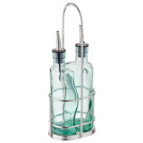 Two green tinted glass bottles with stainless steel pourers are held upright in a silver metal caddy with a handle. Perfect for dispensing oil or vinegar, this Gemelli bottle set keeps your kitchen organized and stylish.