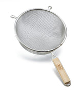 A metal strainer with a double medium mesh and round bowl is shown. It features two small side hooks and a long wooden handle with a brand name, making it ideal for sifting or draining food. The strainer rests on a white background.
