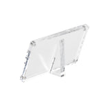 A clear acrylic sign holder stands at an angle, supported by a triangular back stand. The rectangular frame, with visible screws at each corner, is designed to securely display your photo or sign against a plain white background.