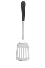A slotted stainless steel turner with a black handle. The spatula features a flat, rectangular head with four long slots for draining and a slightly angled neck. The image is set against a plain white background.