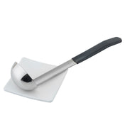 A stainless steel, dishwasher safe soup ladle with a black handle rests diagonally across a small, square white plate. The ladle’s bowl is deep and shiny, reflecting light, and the plate sits on a plain white background.