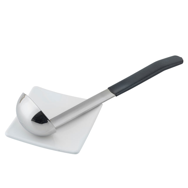 A stainless steel, dishwasher safe soup ladle with a black handle rests diagonally across a small, square white plate. The ladle’s bowl is deep and shiny, reflecting light, and the plate sits on a plain white background.