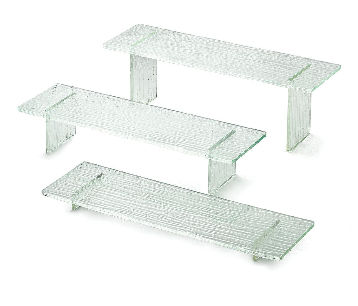 Three clear, textured glass shelves from the Cristal Collection Riser Set are displayed on a white background. Each shelf has two short side supports, creating minimalist, rectangular stands with a subtle striped pattern and transparent green accents.
