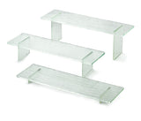 Three clear, textured glass shelves from the Cristal Collection Riser Set are displayed on a white background. Each shelf has two short side supports, creating minimalist, rectangular stands with a subtle striped pattern and transparent green accents.