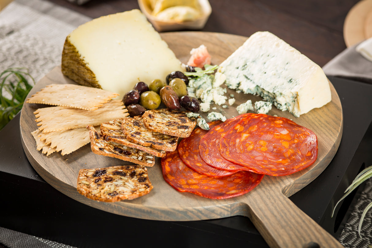 A plate of food is beautifully presented on a TableCraft wood display board, set elegantly on the table.