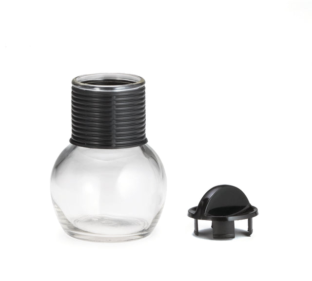 A clear, round glass Hottle with a wide base and a ribbed black plastic neck is shown. Next to it lies a matching lid with a grip knob on a white background. Both the Hottle and lid are dishwasher safe for easy cleaning.
