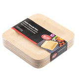 A stack of square, light-colored disposable bamboo plates is wrapped in black packaging labeled “Bamboo Disposable Plates” by TableCraft. The label shows colorful vegetables, highlighting the eco-friendly, compostable square plate design.