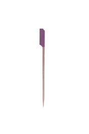 A single TableCraft purple cocktail pick stands vertically against a white background. The top features a small, rectangular purple paper flag, while the bottom tapers to a sharp point. The image is minimal and centered.