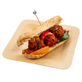 A hoagie roll filled with three large meatballs in tomato sauce, assorted red, yellow, and green bell pepper slices, and onions, served on a square wooden plate and held together with a sport pick topped with a small soccer ball decoration.