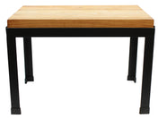 A rectangular table with a thick, light wood butcher block top and sturdy black metal legs. The simple, modern design features clean lines and an industrial style, photographed against a plain white background.