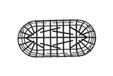 A black powder coated metal serving basket from the Complexity Collection is shown from above. Its oval, wire frame features a grid-like pattern of intersecting straight and curved wires against a plain white background.