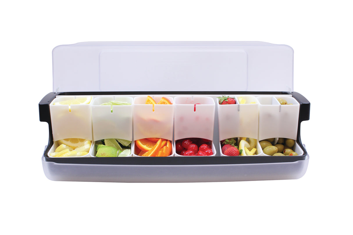 A plastic garnish station with a transparent lid holds six compartments, each filled with different garnishes: lemon wedges, lime wedges, orange slices, maraschino cherries, strawberries, and green olives. NSF certified, set against a plain white background.