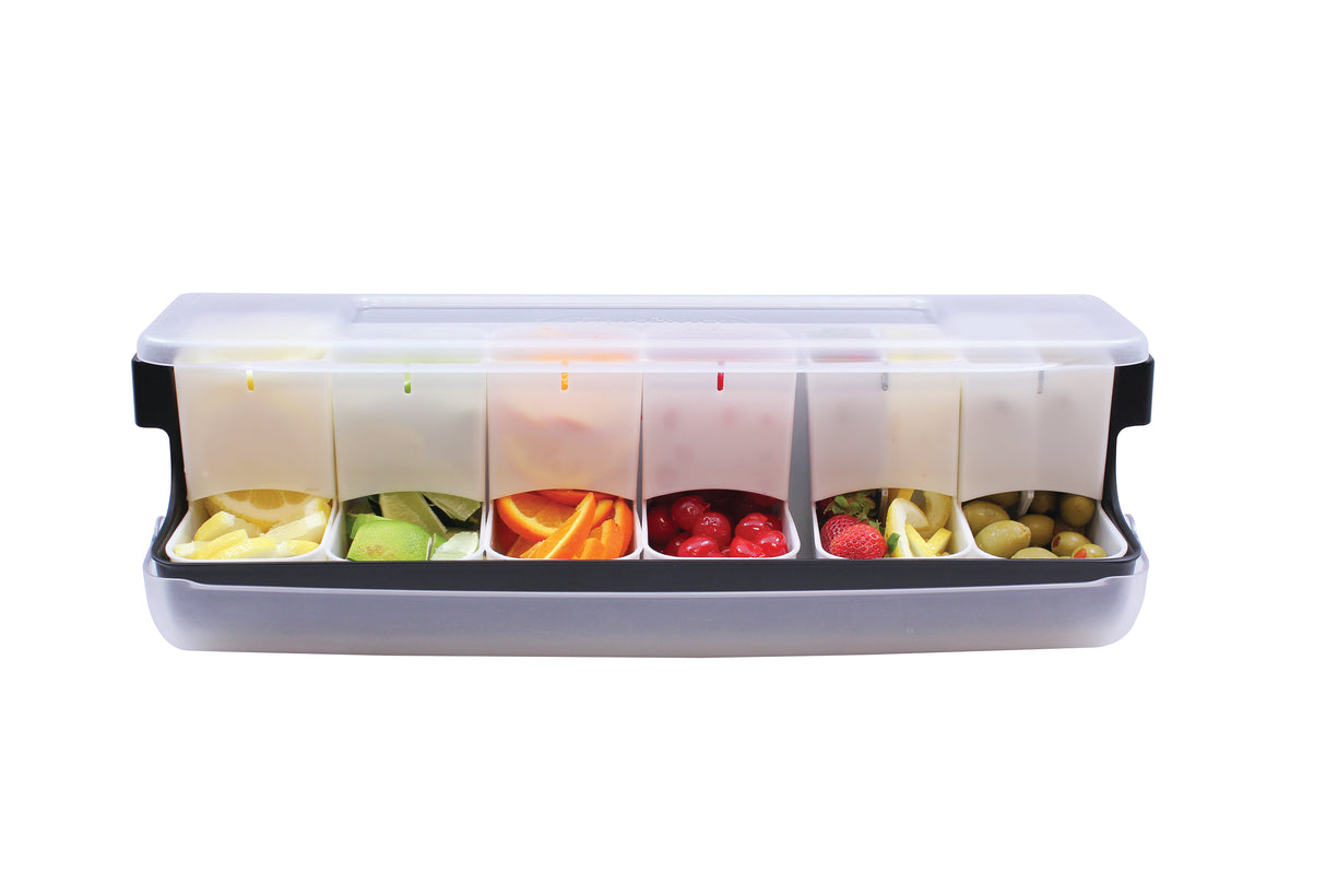 A transparent plastic garnish station with a lid features six compartments filled with lemon wedges, lime wedges, orange peel, cherries, strawberries, and green olives—all organized in a neat row for easy access.