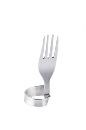 A stainless steel fork is bent so its handle forms a circular loop, allowing it to stand upright as a unique number card holder or fork clip. The prongs point upward, while the handle touches the white surface in an artistic shape.