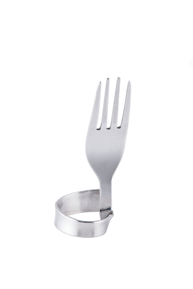 A stainless steel fork is bent so its handle forms a circular loop, allowing it to stand upright as a unique number card holder or fork clip. The prongs point upward, while the handle touches the white surface in an artistic shape.