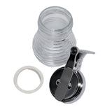 A glass syrup dispenser from the TableCraft Beehive Collection is shown disassembled. The image includes the clear, ribbed glass jar, a white rubber sealing ring, and a shiny metal lid with lever—arranged on a white background.