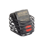 A black powder coated metal wire basket, ideal as a sugar packet holder, displays several dark gray packets labeled “Grated Cheese: Parmesan, Romano & Hard Grating Cheese Blend" with artisan collection style against a white background.