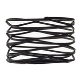 A black powder coated metal wave spring with a helical, layered structure is shown against a white background. Part of the Artisan Collection, its thin, flat bands form a zigzag pattern, resembling a unique Sugar Packet Holder.