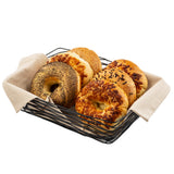 A rectangular serving basket from the Artisan Collection, crafted in black powder coated metal and lined with beige cloth, holds six assorted bagels—poppy seed, sesame, cheese, and onion—neatly arranged on a white background.