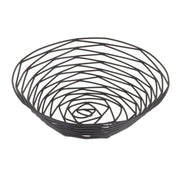 A round, open wire basket from the TableCraft Products Artisan Collection, featuring a modern geometric spiral design in black powder coated metal. Its shallow depth and wide opening create a visually airy and minimalist look with a slightly raised base.