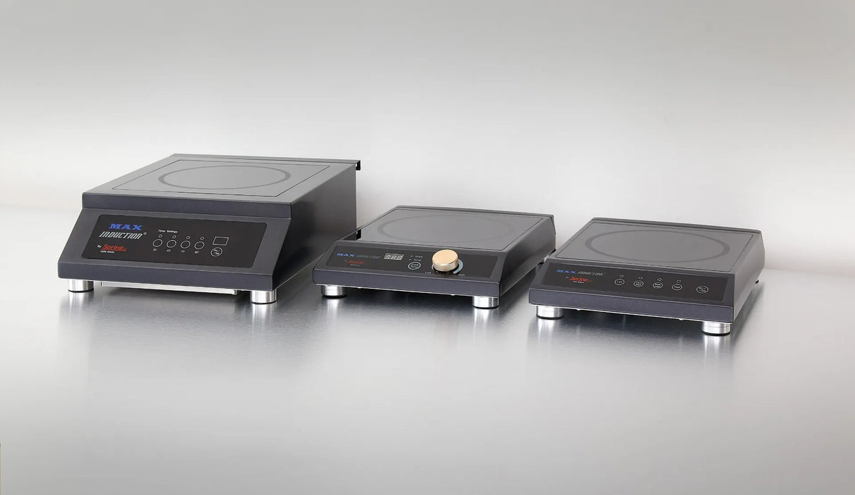 Three modern black countertop induction cooktops with metal legs are displayed on a reflective silver surface against a plain light gray background. Each features a circular cooking zone and front-panel controls, perfect for any contemporary kitchen.
