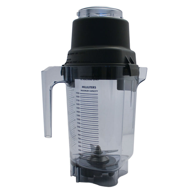A clear plastic Vitamix container with measurement markings in milliliters, a black handle, and black lid. Metal blender blades are visible at the bottom. This 64 oz blender jar stands upright on a white background.