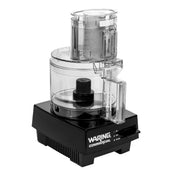 A clear 1.7 liter workbowl with a handle sits on a black rectangular Waring Food Processor base labeled “Waring Commercial.” The appliance features an on/off switch, pulse function, and a lid with feed tube and pusher for international use.