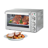 A stainless steel commercial convection oven with roast meat and vegetables inside, viewed through a glass door. Three control knobs and indicator lights are on the right. In front, a plate holds two slices of roasted meat and assorted vegetables.