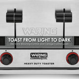 Close-up of a stainless steel Waring heavy-duty toaster with 4 slice capacity. Two black levers and red-banded control knobs are visible. Text reads: TOAST FROM LIGHT TO DARK. Electronic Browning Controls and Carriage Control Levers.