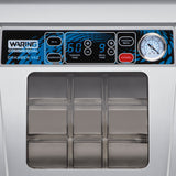 Close-up of a Waring Vacuum Packaging Machine control panel. Display shows “60” for vacuum time and “9” for seal time. Countertop unit features Seal, Marinate, Vacuum Seal, and Cancel buttons, a pressure gauge, and part of the chamber lid below.