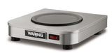 A stainless steel single burner electric hot plate with a smooth black heating surface, red power switch, and four short legs. The Waring brand name is displayed on the front. Its modern, compact design makes it ideal as a coffee warmer or for quick meals.