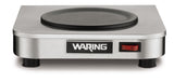 A stainless steel Waring single-burner electric hot plate, ideal as a coffee warmer, is shown from the front. It features a black round heating surface, a red on/off switch to the right, and stands on four black feet.