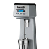 A silver Waring WDM120TX Drink Mixer with a digital blue LCD timer display, speed and pulse buttons, and a stainless steel mixing cup attached underneath the single spindle on a white background.