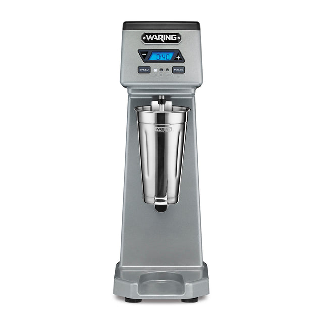 The Waring WDM120TX Single Spindle Drink Mixer features a digital display, control buttons, and a stainless steel mixing cup at the center. This sturdy countertop appliance boasts a modern, professional appearance for any kitchen or bar.