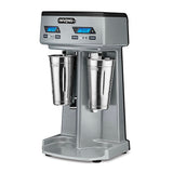 A silver Waring commercial drink mixer with a double spindle, two stainless steel mixing cups, digital timers, and control buttons on a sleek black and silver panel—all designed for countertop use against a white background.