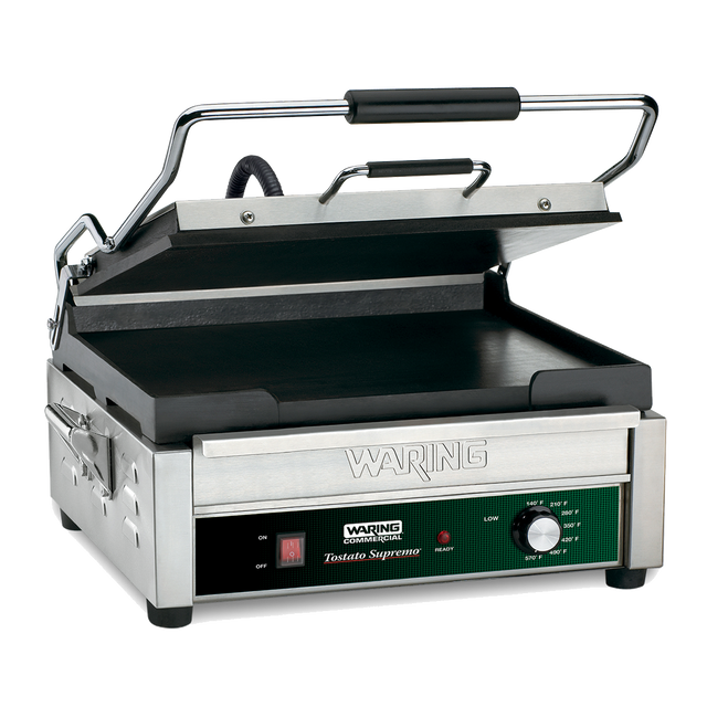 A stainless steel Waring commercial panini grill with a partially open ribbed top plate, flat cast iron cooking surface, black handle, side handles, and a front control panel featuring an adjustable thermostat and labeled Waring Tostato Supremo.