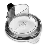 A clear plastic Waring Sealed Bowl Cover for food processors, featuring a built-in feed chute. The round lid has measurement markings, a locking mechanism, and fits WFP16S models for easy ingredient addition while processing.