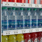 Plastic bottles of Dasani water are lined up in a refrigerated display, each with an ESM-36W price tag reading $1.79. Above are cans of Coke and Diet Coke, and below are yellow Gatorade bottles, all with clear price tags from a price tag set.