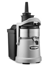 A heavy duty Waring juice extractor in silver and black features a large spout, top funnel for produce, side handle, and a black container on the left for continuous pulp ejection; the Waring logo is displayed on the front.