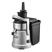 A heavy duty silver and black juice extractor with a cylindrical metal body, continuous pulp ejection, a side handle, top plunger, black plastic pulp container on the side, spout for dispensing juice, and a green power switch at the base.
