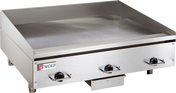 A commercial electric griddle featuring three black control knobs, raised side and back splashes, and a small Wolf brand logo on the front left corner. This stainless steel griddle offers a flat cooking surface with a grease tray beneath the front edge.