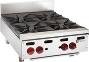 A stainless steel commercial hotplate with four black cast iron burners, red control knobs, and metal legs. The Wolf logo is visible on the front panel. This professional kitchen appliance features a raised backguard and a modern, industrial design.