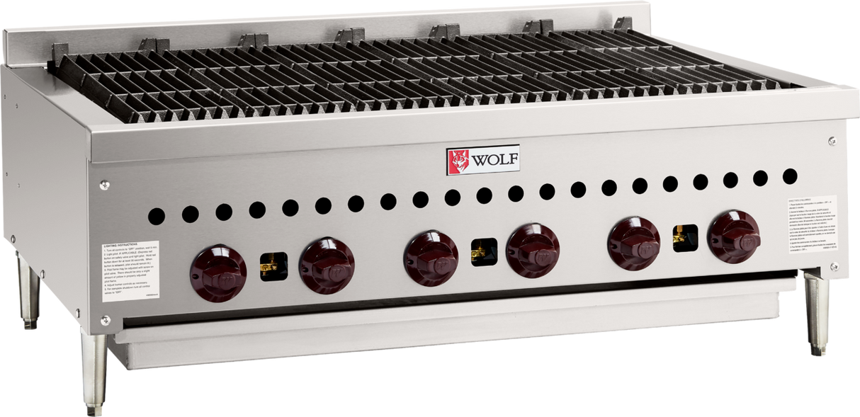 A stainless steel commercial gas charbroiler with six red control knobs, grated grilling surface, Wolf brand logo on the front, and four sturdy legs. Ideal for professional kitchen grilling, with ventilation holes and safety labels on both sides.