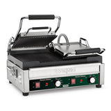 A stainless steel electric panini grill with ridged top and bottom plates, both with black handles. The front panel features two red switches, temperature dials, indicator lights, and the Waring brand above the controls. The top plate is open.