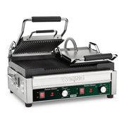 A stainless steel electric panini grill with ridged top and bottom plates, both with black handles. The front panel features two red switches, temperature dials, indicator lights, and the Waring brand above the controls. The top plate is open.