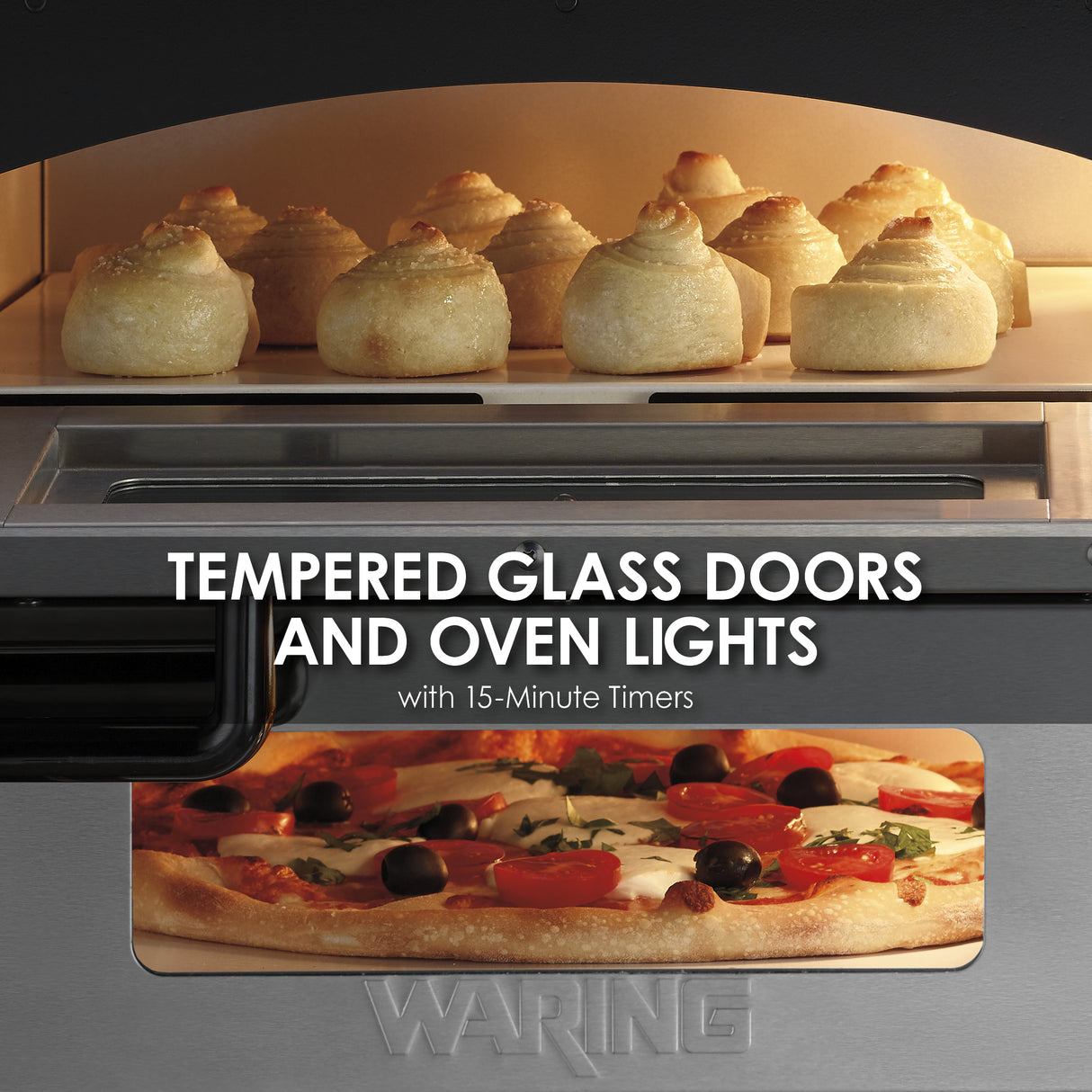 Close-up of a double-deck pizza oven with bread rolls baking on the top rack and a pizza with tomatoes, olives, and cheese below. Text over the oven reads, “Tempered glass doors and oven lights with 15-minute timers.”.