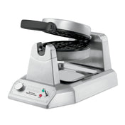 A heavy-duty stainless steel Belgian Waffle Maker with a rotating circular plate, angled base, indicator lights, control knob, and drip tray. The open waffle plates reveal a nonstick grid pattern perfect for international use.