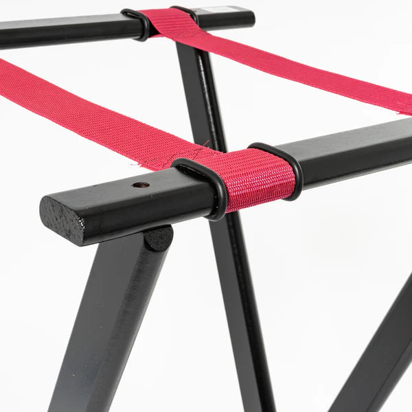 Close-up of a Deluxe tray stand with a sleek black metal frame, two sturdy, flat legs, and red fabric straps stretched across the top. The plain white background highlights the rack’s structure and materials.